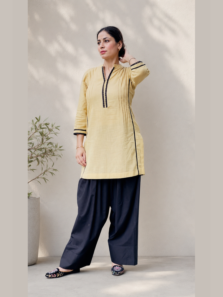 Beige women’s kurta with black detailing and black farshi salwar by Lush Layers