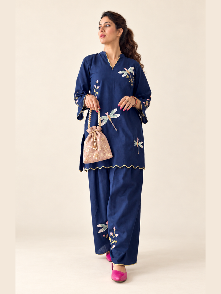  Lush Layers navy dragonfly embroidered co-ord set, crafted from a premium soft cotton–lyocell blend for effortless everyday elegance. Navy dragonfly embroidered cotton–lyocell co-ord set with matching trousers by Lush Layers. Softness, with a little detail.
Navy Dragonfly Co-ord Set